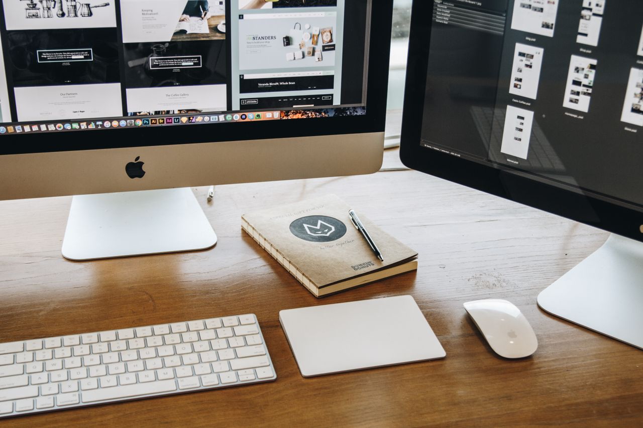 hero-img A minimalist desk setup featuring dual monitors, keyboard, mouse, and notebook for productivity.