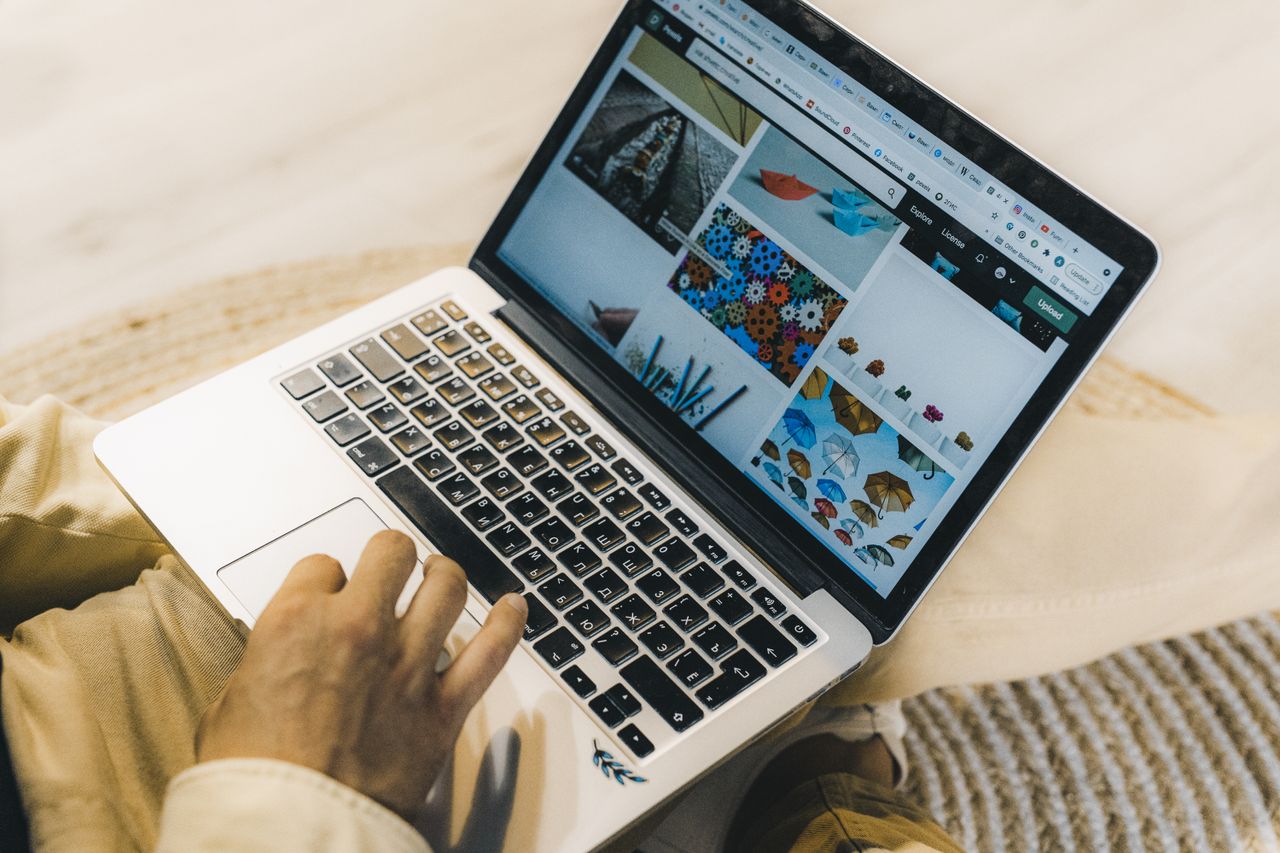 about-01 A person using a laptop to browse stock photo websites. Freelancing work in a cozy setting.